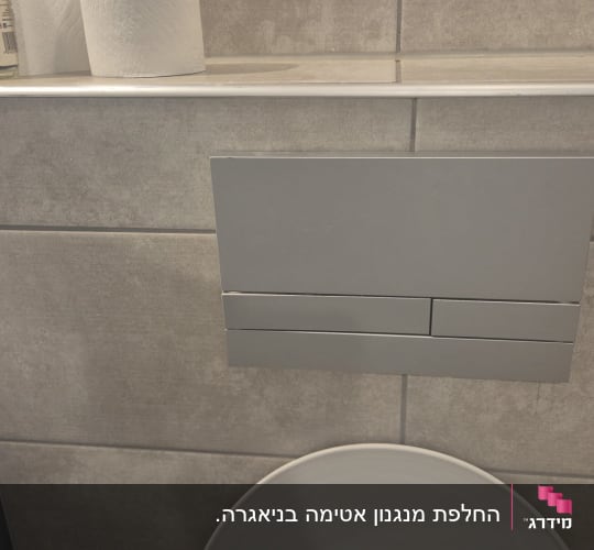 לחצן הפעלה כסוף לניאגרה סמויה המותקן על קיר אריחים בשירותים
